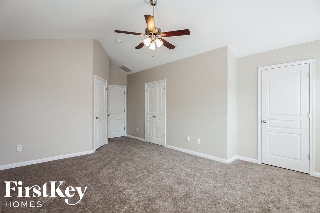 A room with a ceiling fan and carpeted floor.