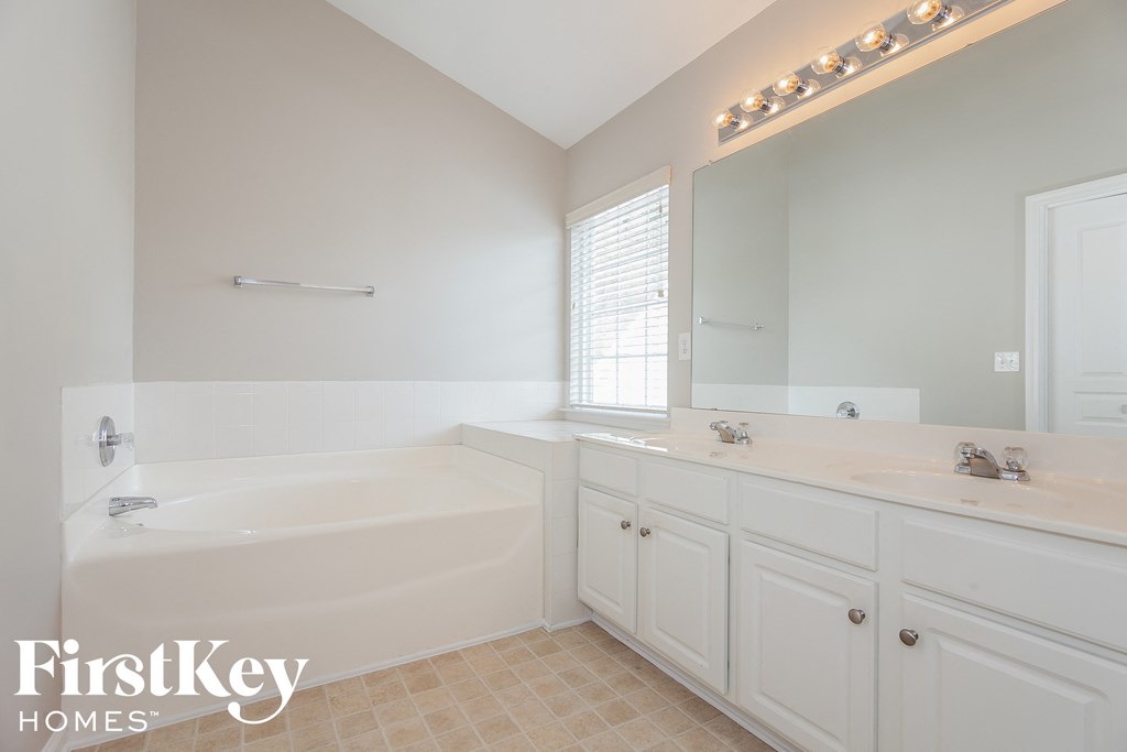 A white bathroom with a tub, sink, and mirror.