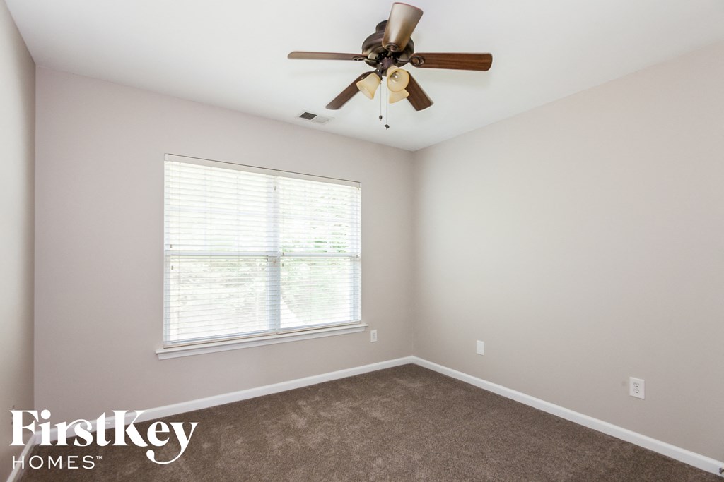 A room with a ceiling fan and a window with blinds.