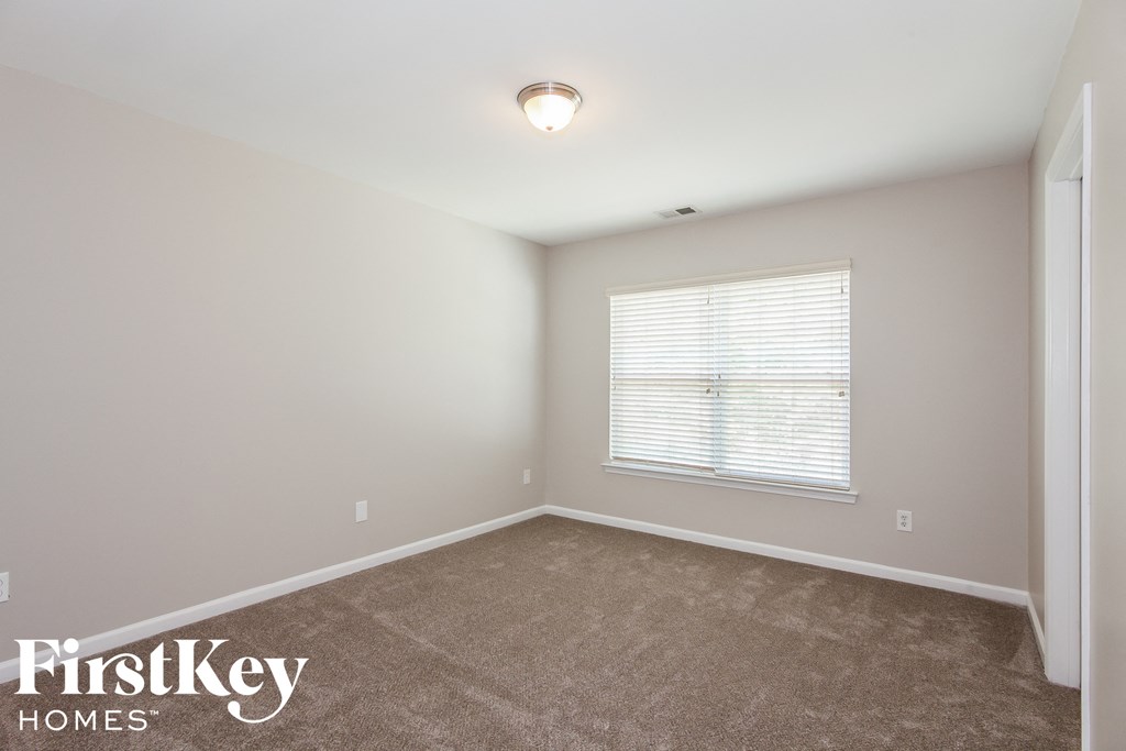 A room with a carpeted floor and a window with blinds.