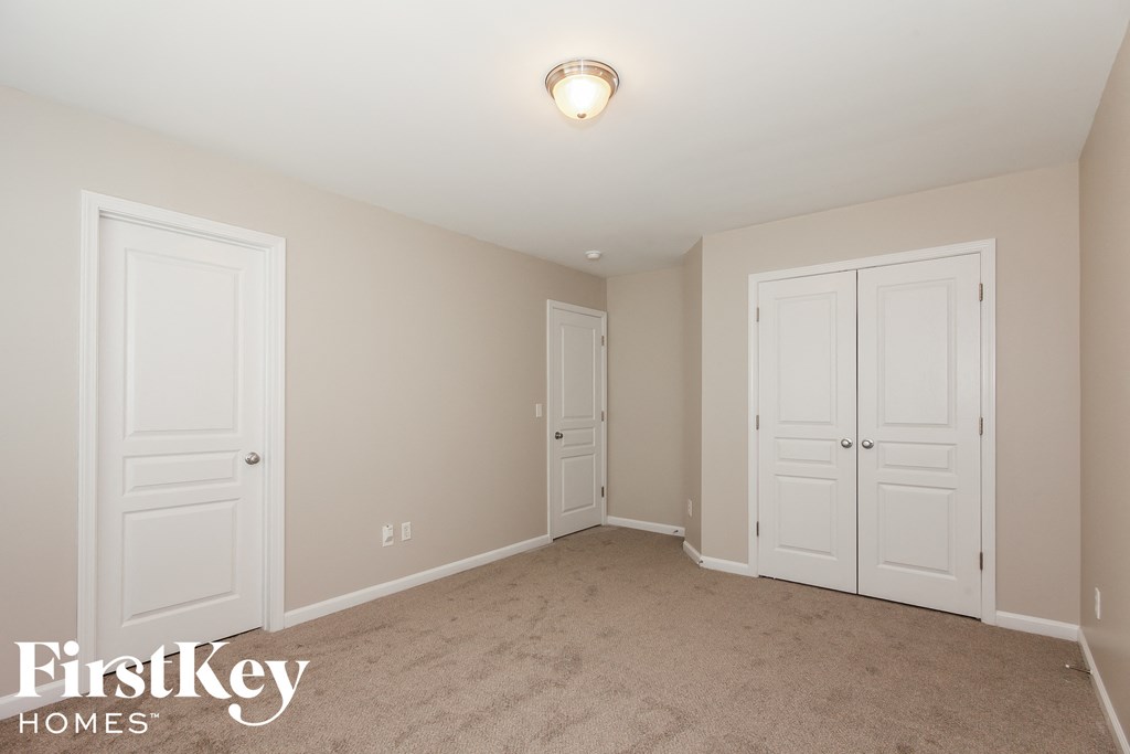 A bedroom with a white door and a carpeted floor.