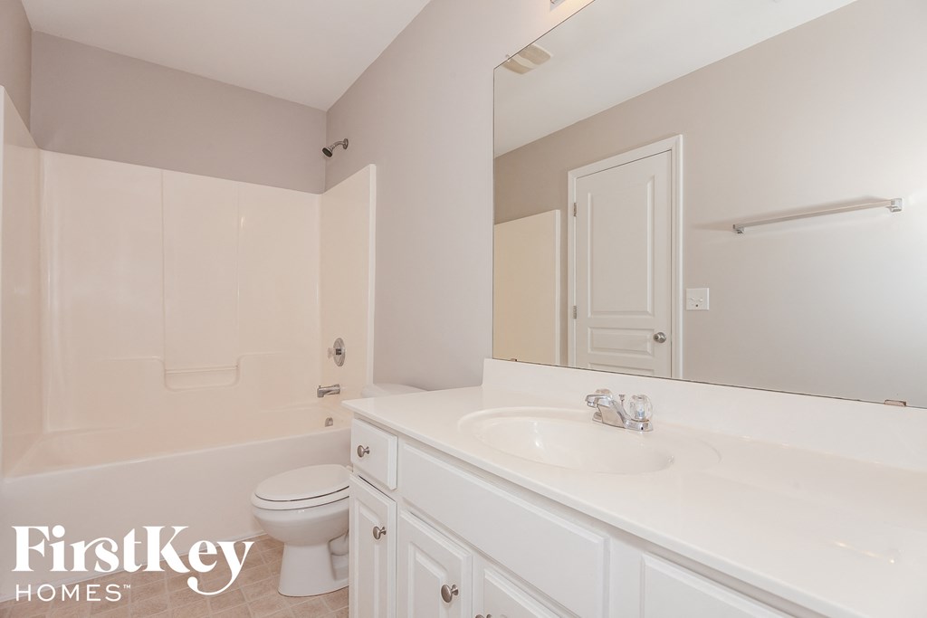 A white bathroom with a toilet, sink, and mirror.