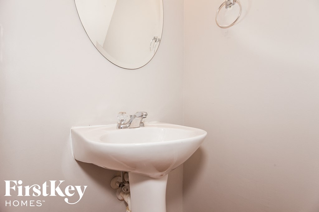 A white sink with a round mirror above it.