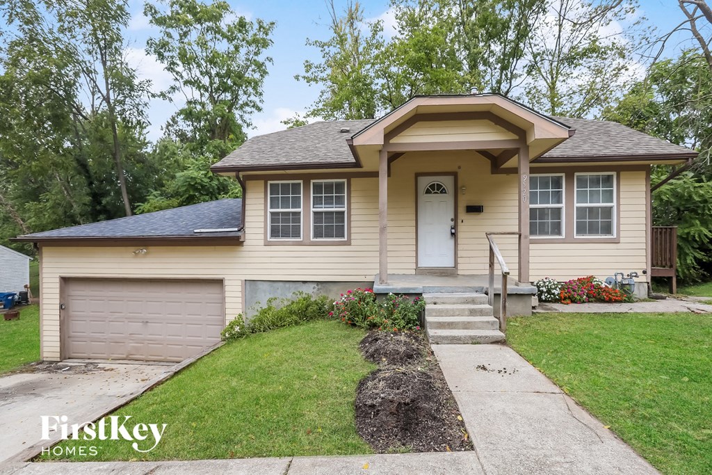 the front of a yellow house with a driveway and a garage door