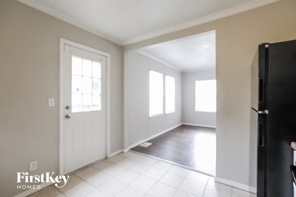an empty living room with a white door and a black refrigerator