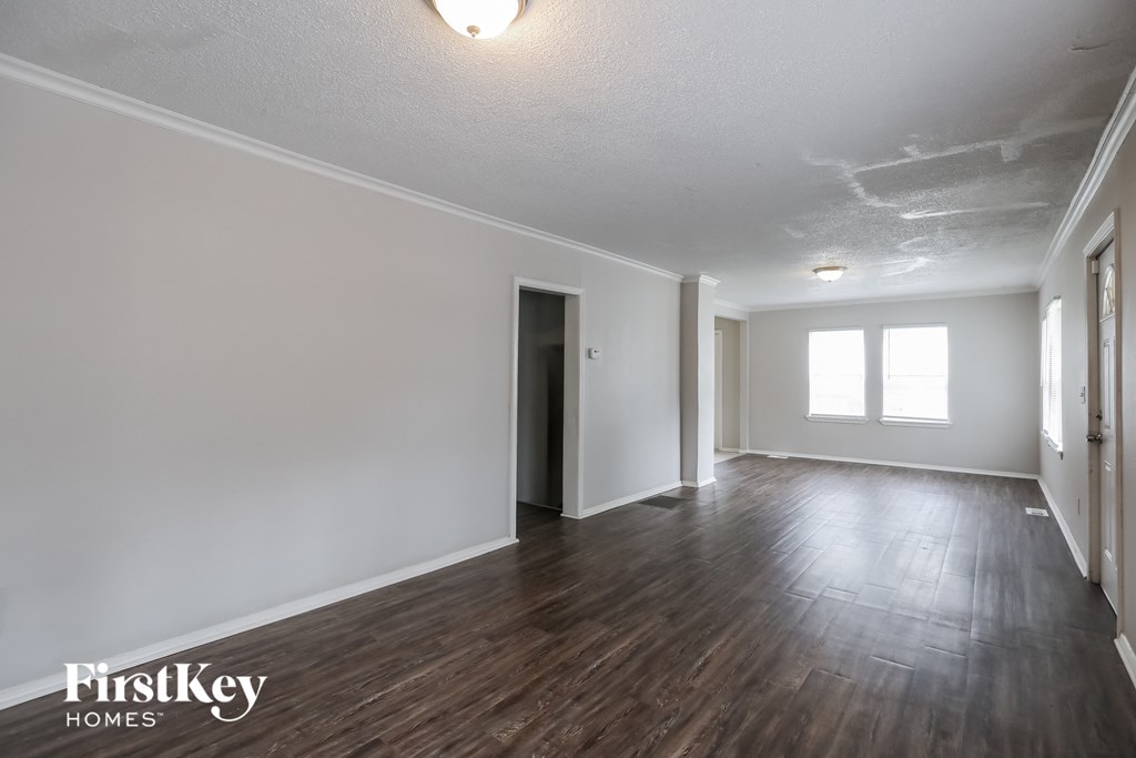 the living room and dining room of an empty house with white walls and wood floors