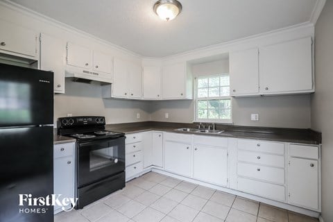 a kitchen with white cabinets and black counter tops and black appliances