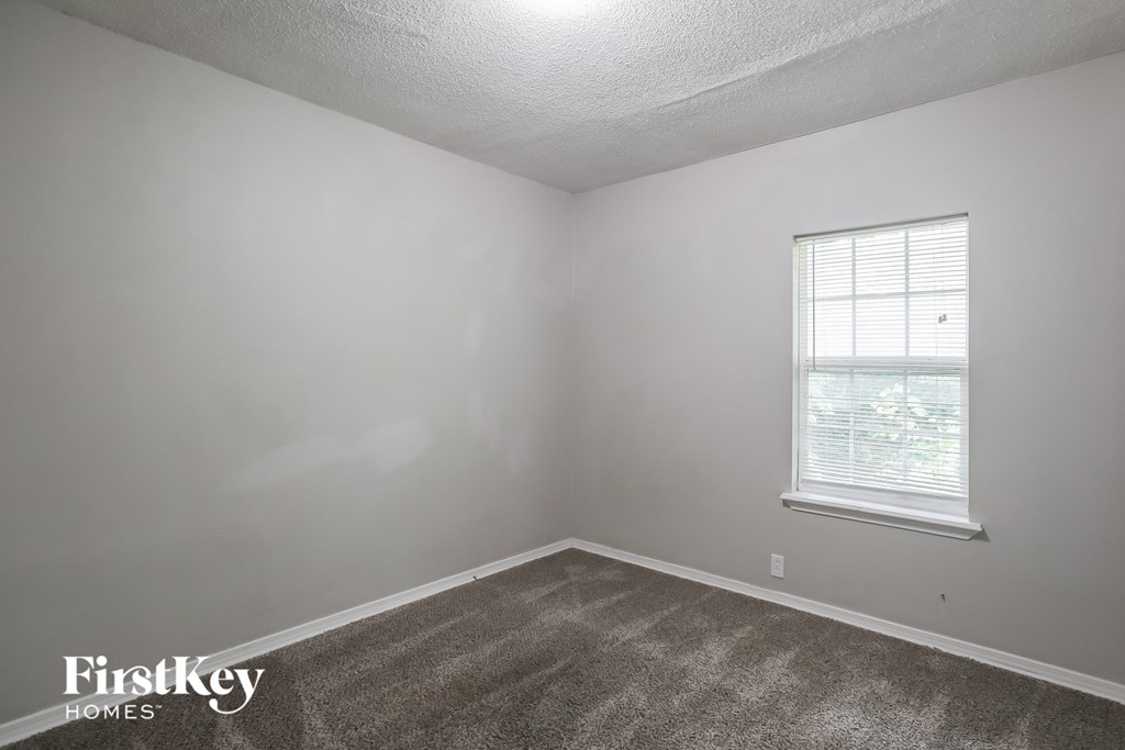 a bedroom with white walls and a window