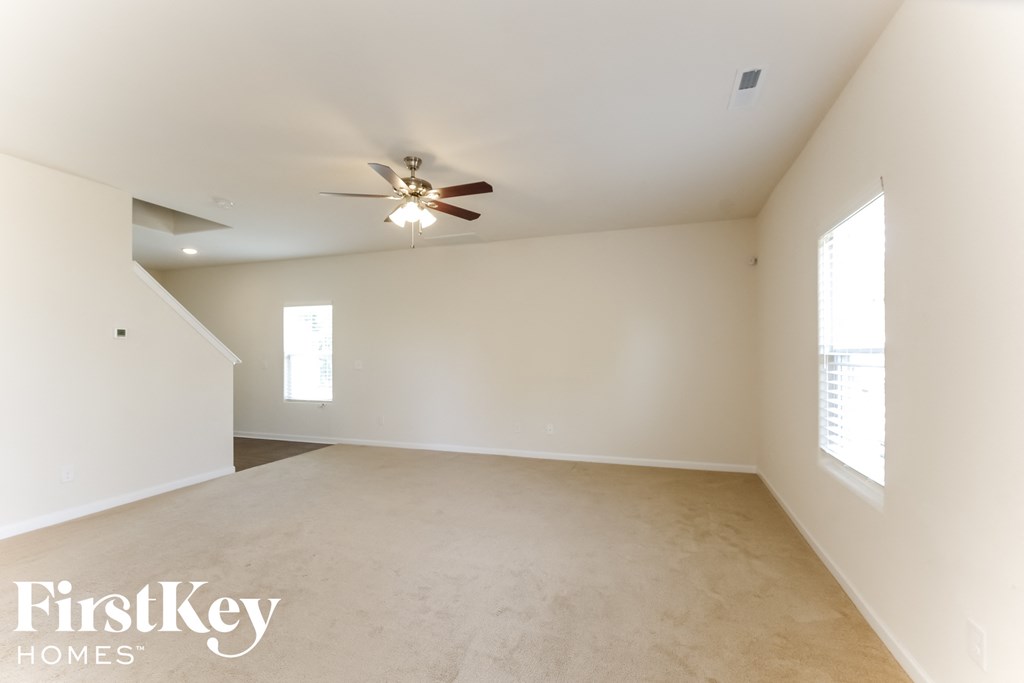 A spacious room with a ceiling fan and two windows.