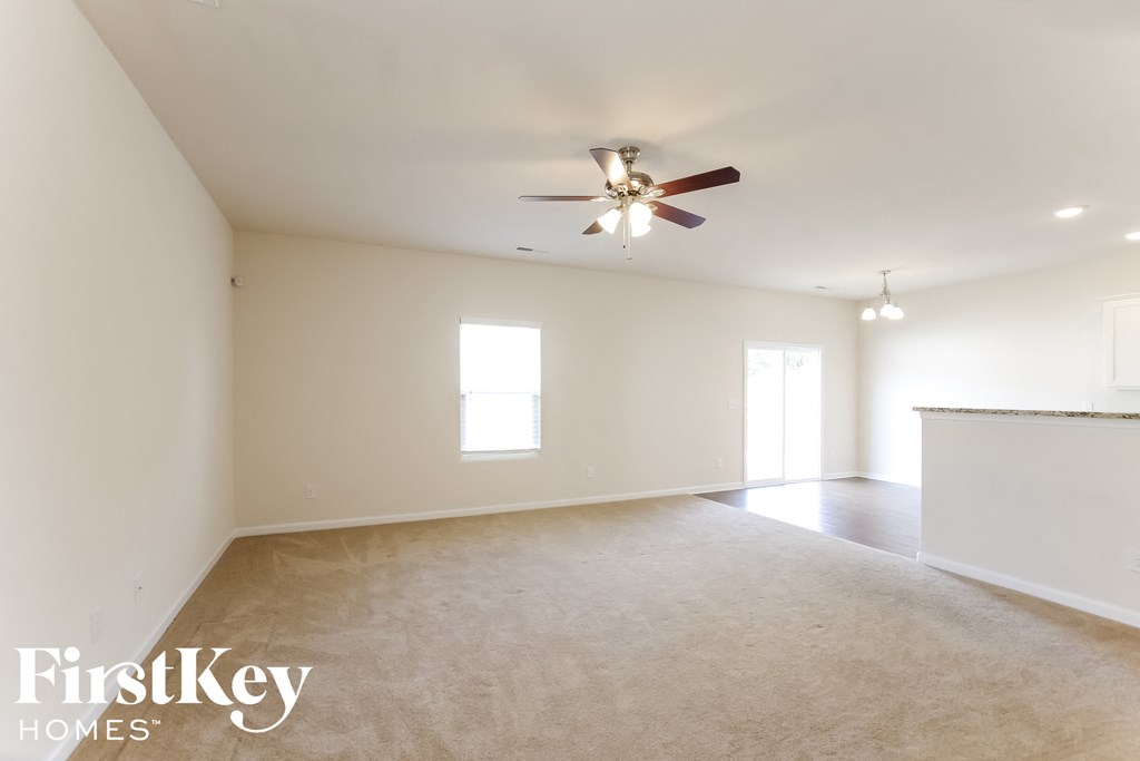 A spacious room with a ceiling fan and two windows.
