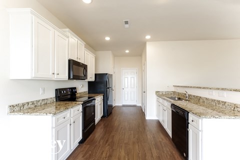 A kitchen with white cabinets and granite countertops.
