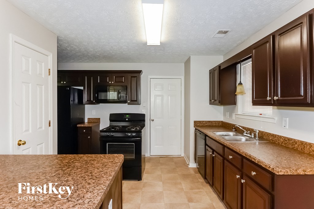 a kitchen with brown cabinets and granite counter tops and a black stove