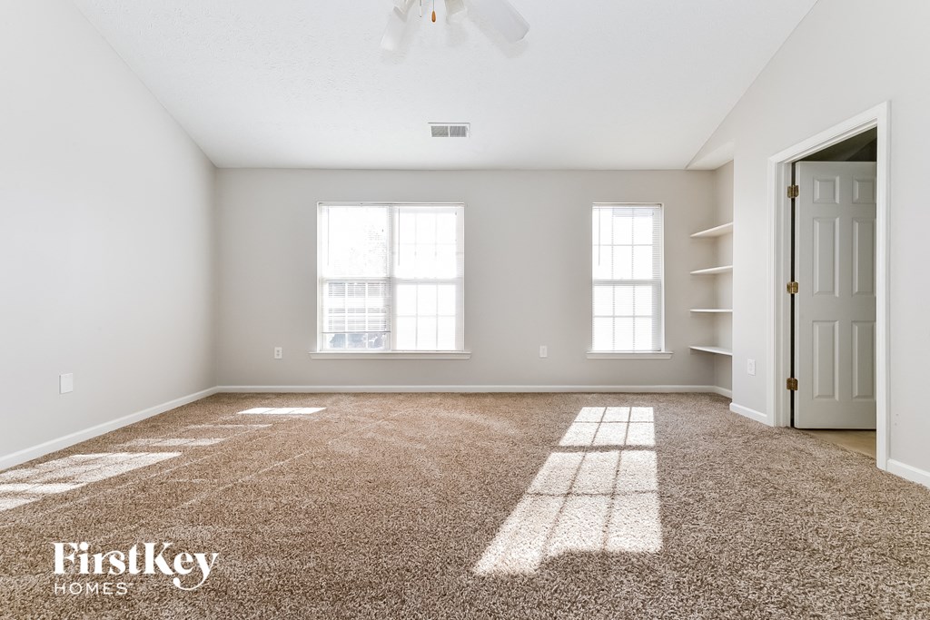 the spacious living room with a door to the hallway and carpeted flooring