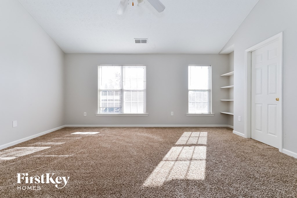 an empty room with a closet and two windows