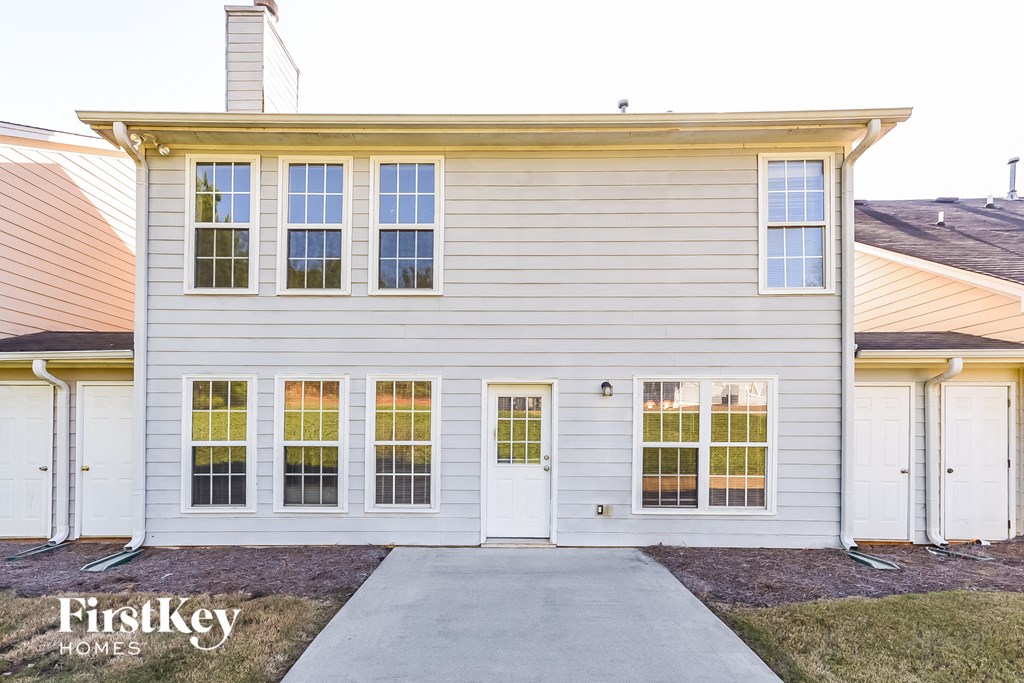 the exterior of a white house with white siding and a driveway