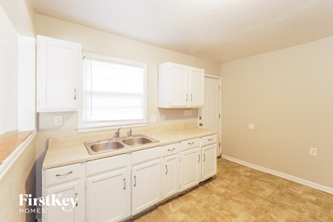 a kitchen with white cabinets and a sink and a window