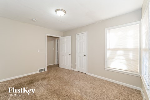 a bedroom with a carpeted floor and a door to a closet