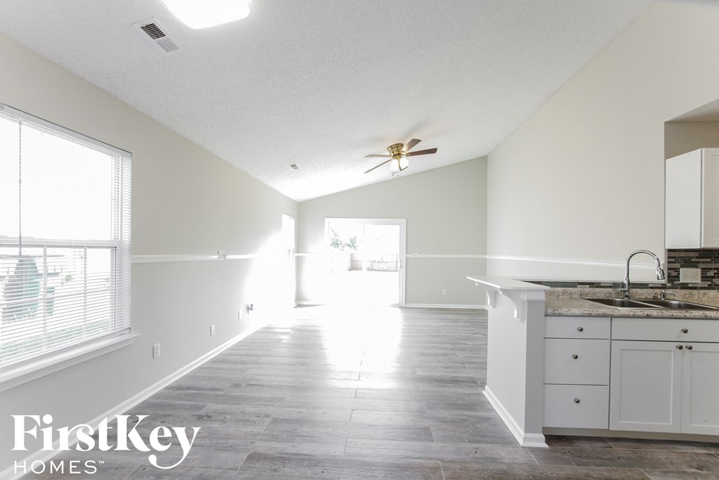 an empty kitchen with white cabinets and a ceiling fan
