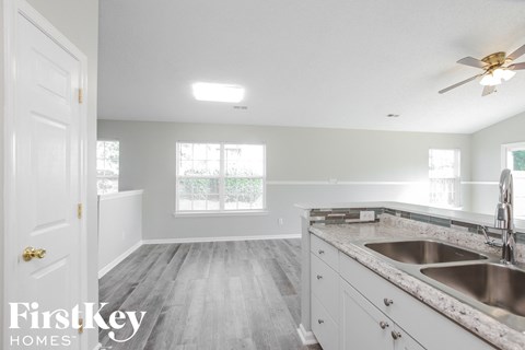 a kitchen with white cabinets and a sink and a ceiling fan