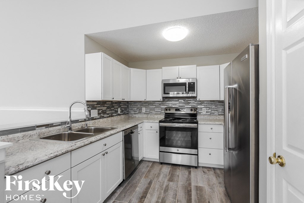 a white kitchen with stainless steel appliances and white cabinets