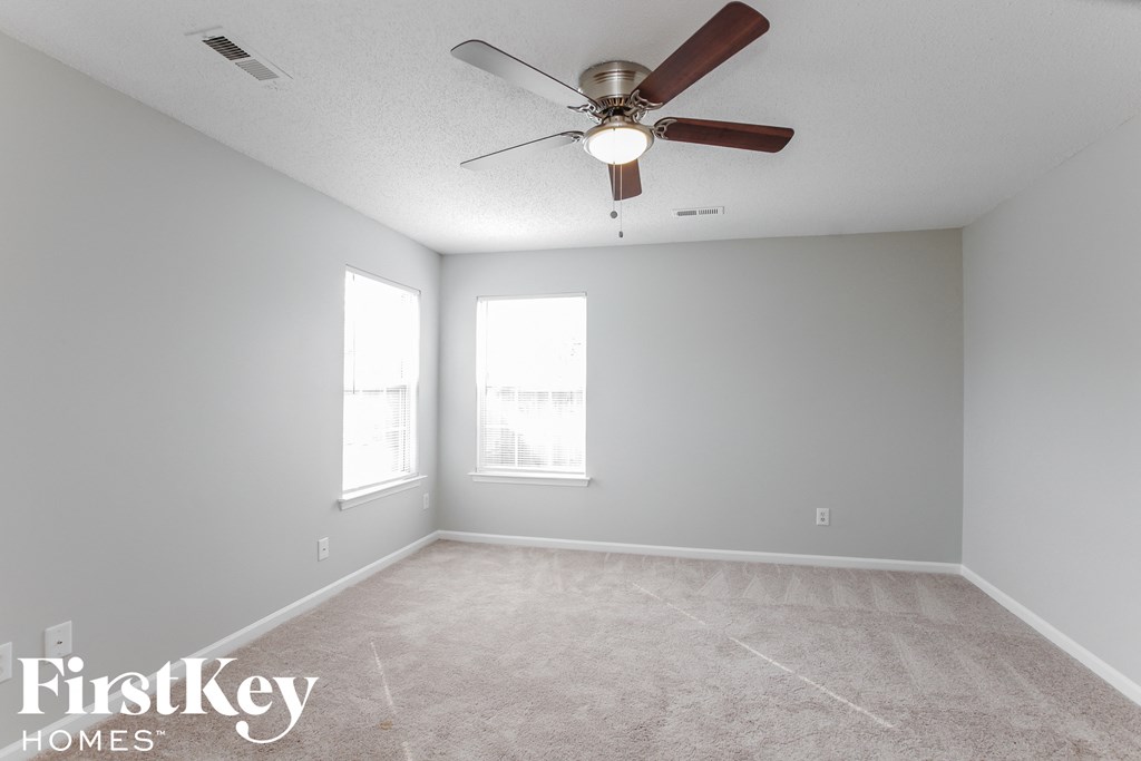 a empty room with a ceiling fan and two windows
