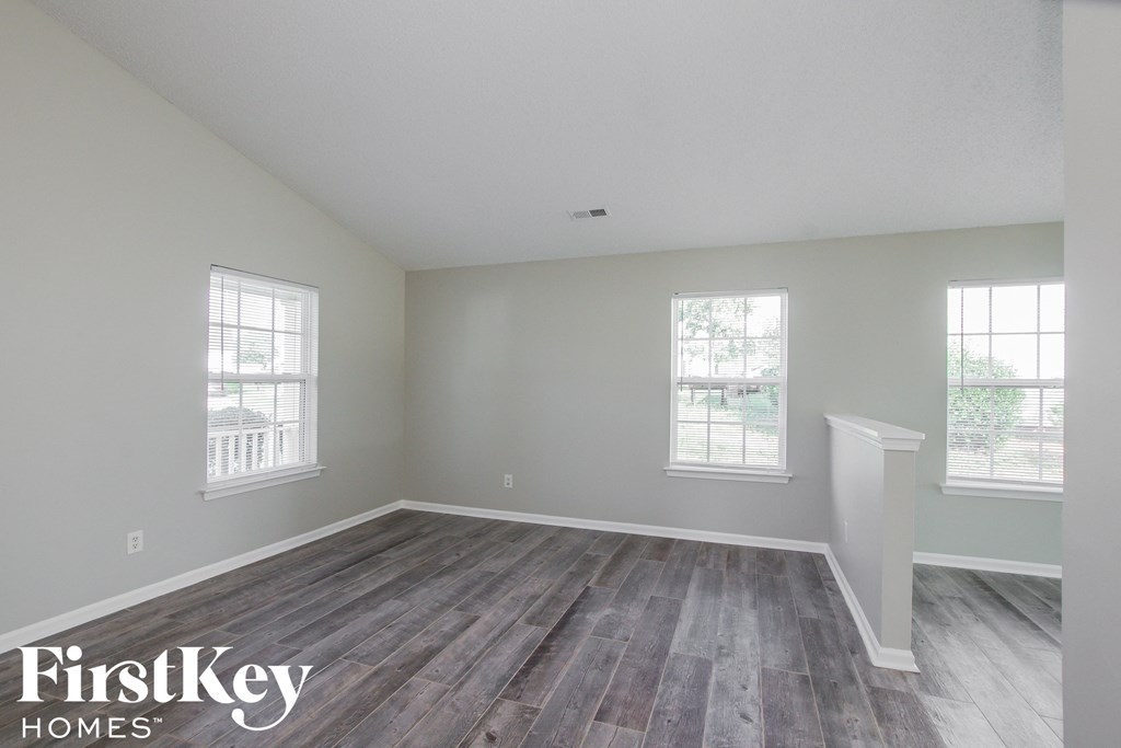 the spacious living room with hardwood flooring and two windows