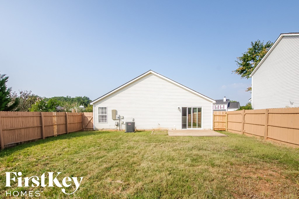 a backyard with a white house and a wooden fence