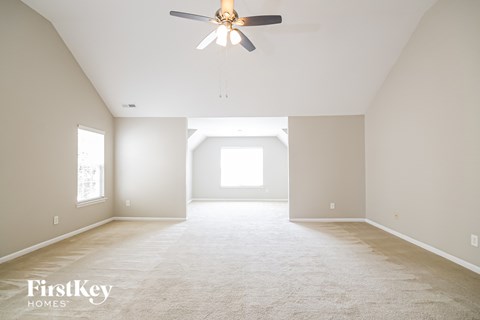 A spacious room with a ceiling fan and carpeted floor.