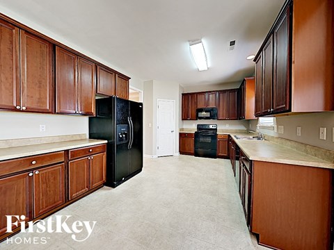 A kitchen with wooden cabinets and a black fridge.