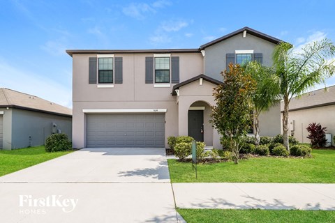 a beige house with a garage door and a lawn