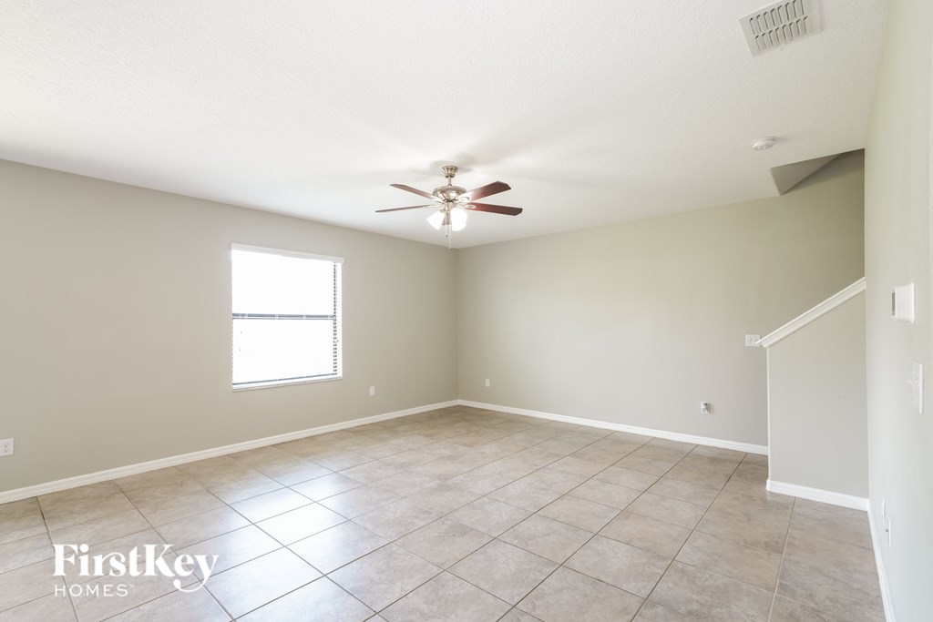 an empty living room with a ceiling fan
