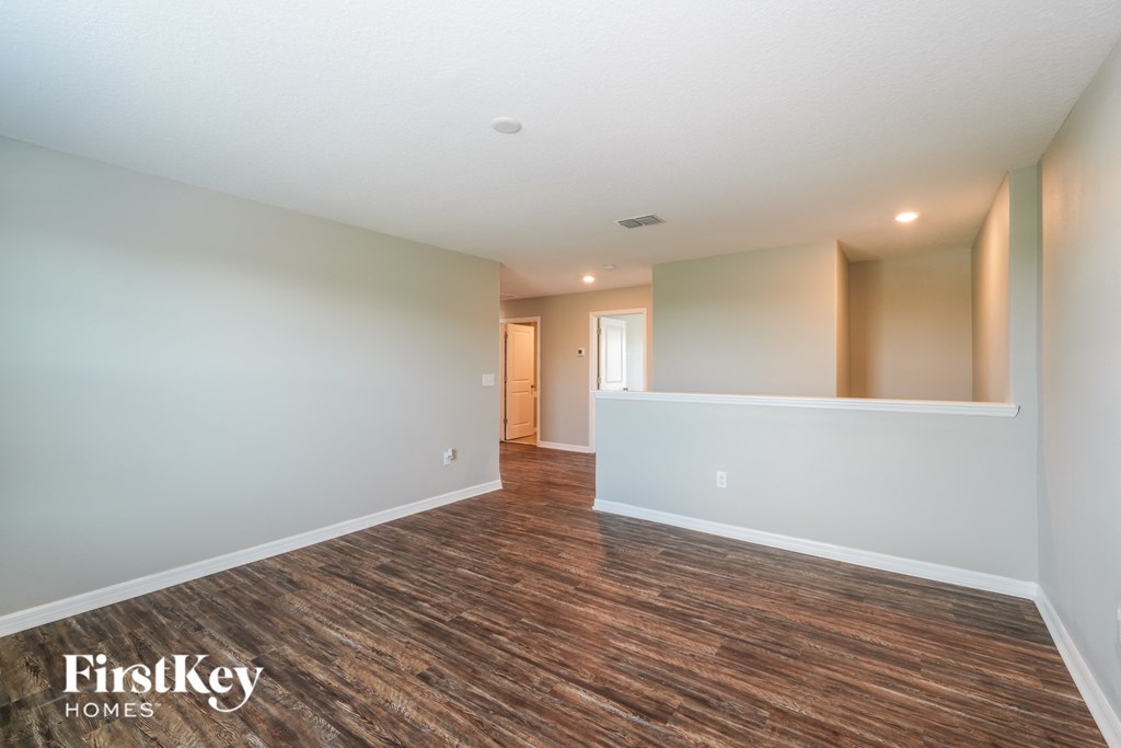 the living room and dining room of a house with white walls and wood flooring