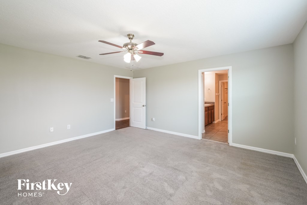 a empty living room with a ceiling fan and a carpet
