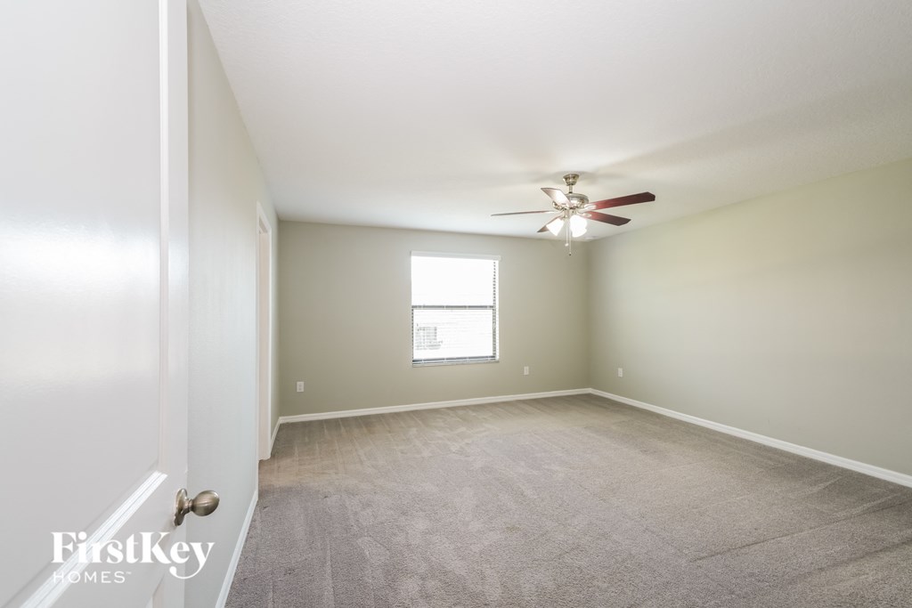 an empty living room with a ceiling fan and a window
