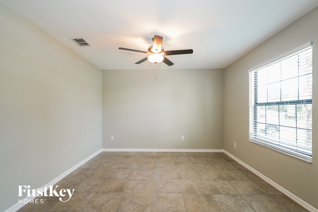 an empty room with a ceiling fan and a window
