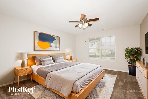 A bedroom with a bed, nightstand, and a painting on the wall.