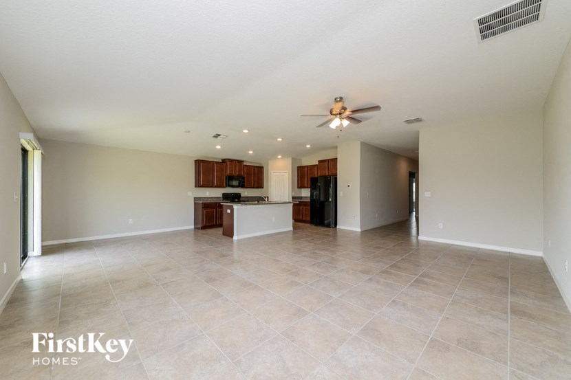 an empty living room and kitchen with a ceiling fan