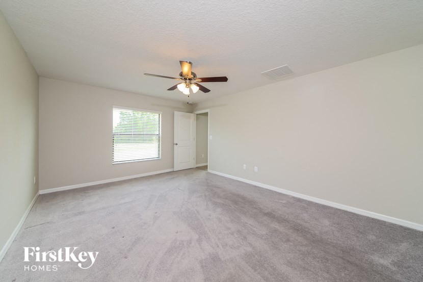 the living room is spacious and has a ceiling fan