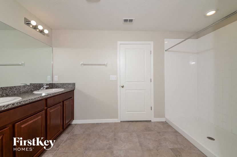 the master bathroom has two sinks and a shower and a large mirror