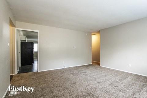 A spacious, empty room with a carpeted floor and a doorway leading to another room.