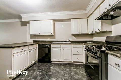 A kitchen with a black stove top oven and white cabinets.