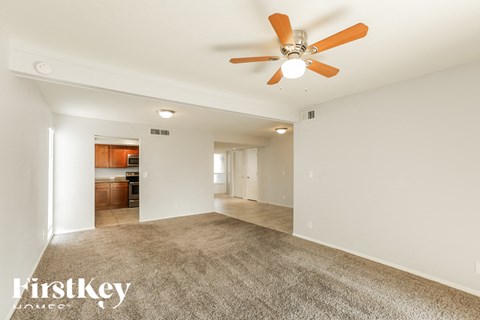A spacious room with a ceiling fan and carpeted floor.