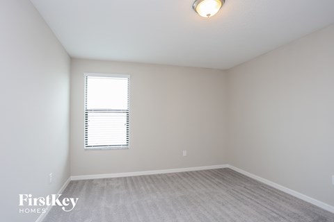 a bedroom with white walls and a window and a white carpet