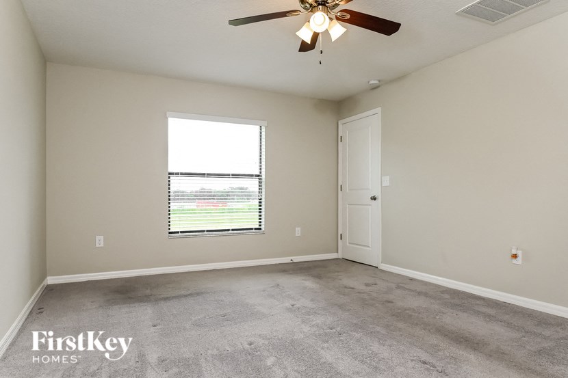 an empty living room with a window and a ceiling fan