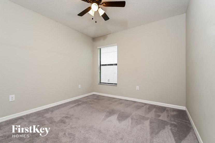 an empty living room with a ceiling fan and a window