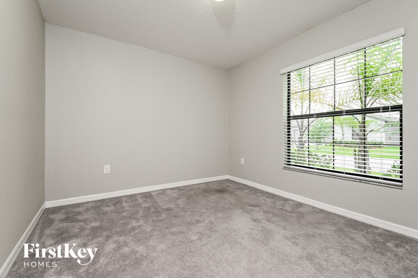an empty bedroom with a large window and carpeting