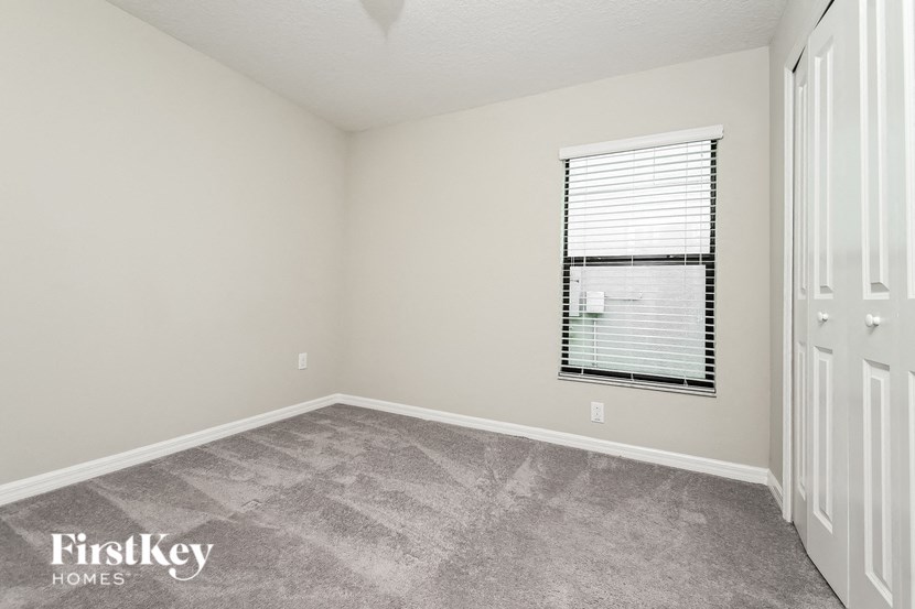 a bedroom with a window and a carpeted floor
