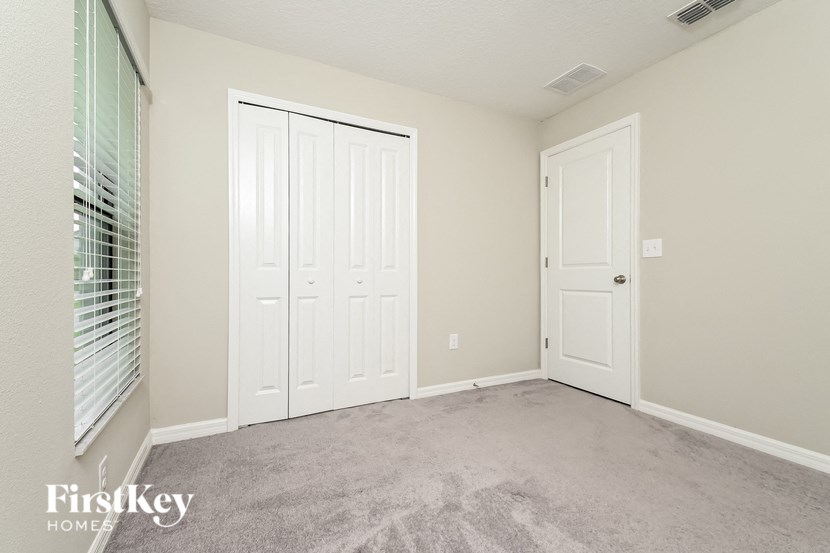 a bedroom with two doors and a window and a carpeted floor