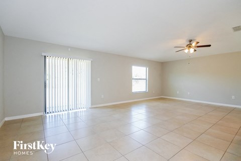 A spacious room with a ceiling fan and a window with blinds.