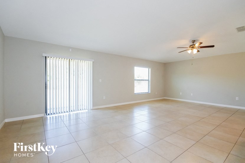 A spacious room with a ceiling fan and a window with blinds.